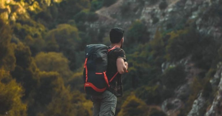 Hiking - Man in Black T-shirt Carrying a Bag-pack Standing on Cliff