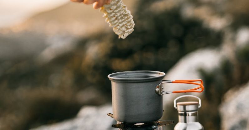 Outdoor Cooking - A Hand Putting Noodles on a Cooking Pot