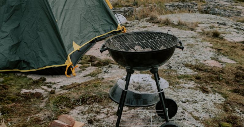 Outdoor Cooking - Food Lying on the Ground next to a Grill and a Tent on the Seashore