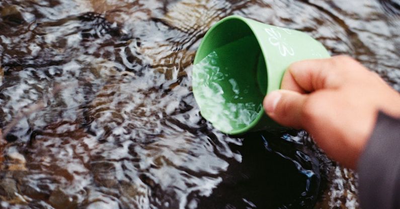 Bushcraft - Person Scooping Water Using Green Cup