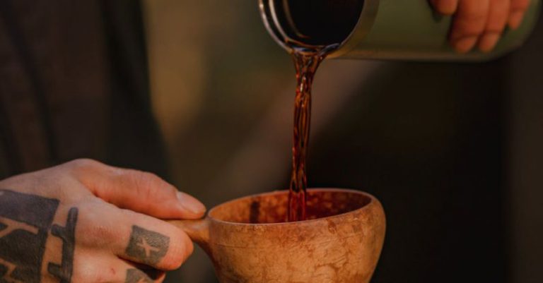 Bushcraft - Photo of a Person Pouring a Drink from a Thermos Bottle into a Clay Cup