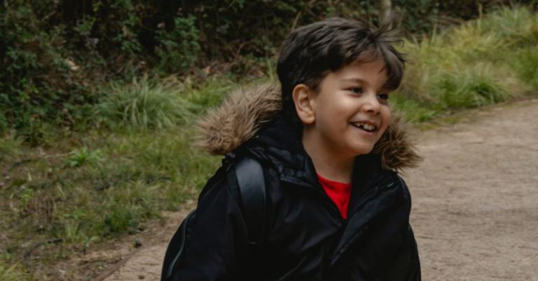 Trail Hike - A young boy in a black jacket and black pants walking on a dirt path