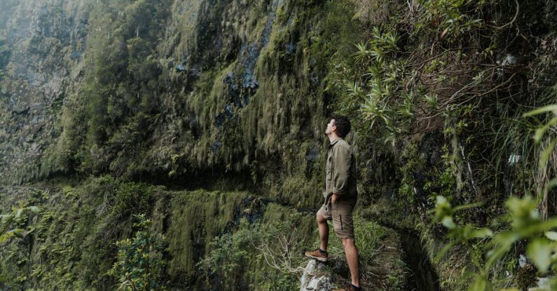 Trail Hike - Man Standing on Trail by Cliff and Looking Up